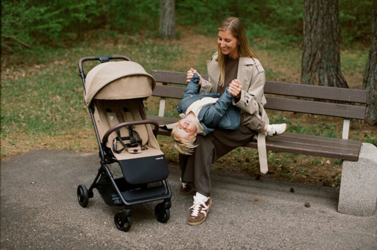 Mother and child resting on a park bench next to Sia
