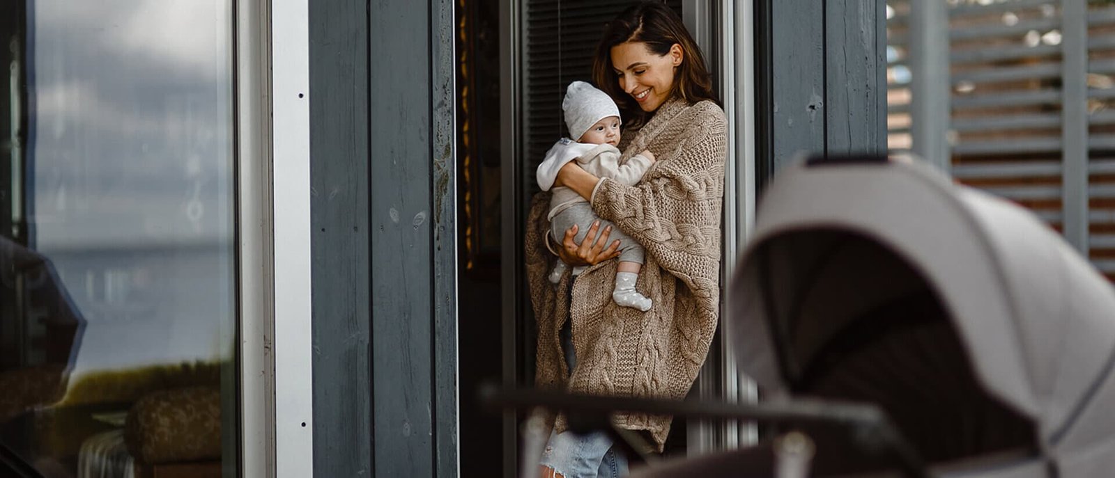 Mama su kūdikiu prie durų, šalia – Noordi vežimėlis