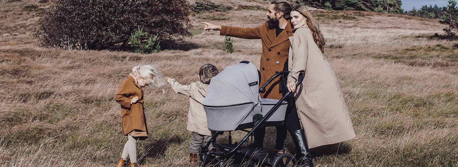 Family walking through an autumn heath with a small child and a pram