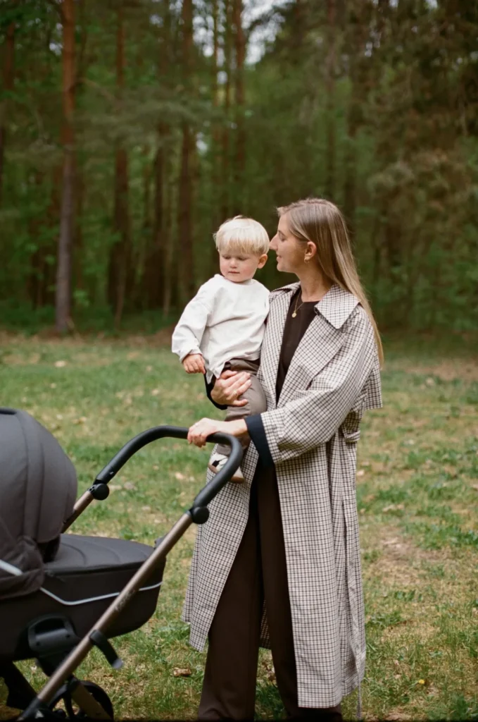 Mother holding her child next to a Noordi Fjordi V.2 pram in the forest