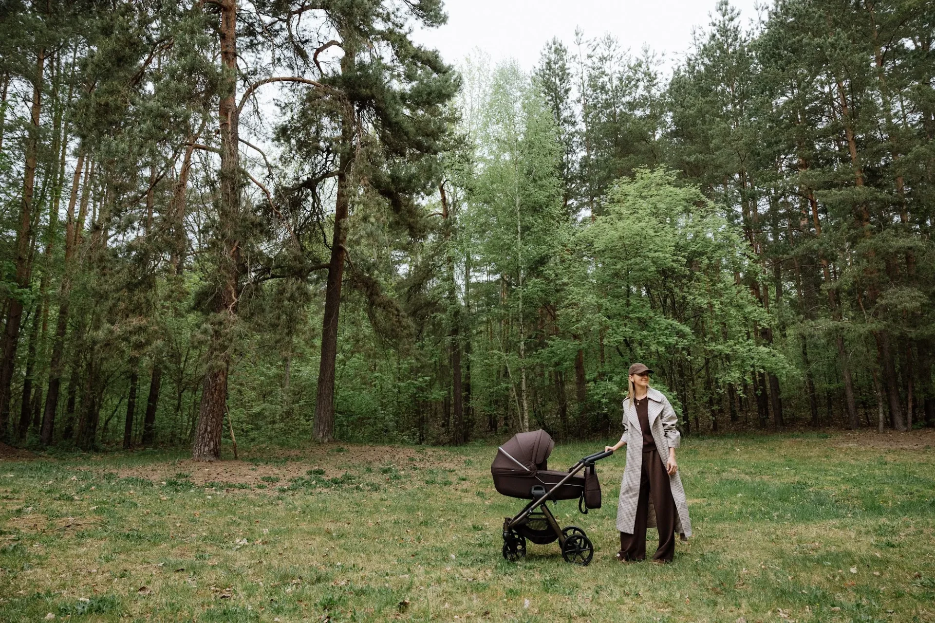 Mutter mit dem Noordi Fjordi V.2 Kinderwagen auf einer Lichtung im Kiefernwald