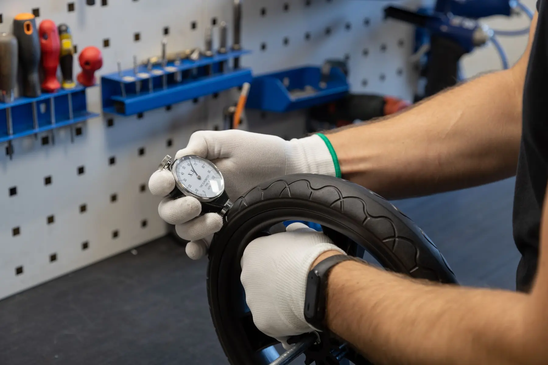 Gloved hands measuring the hardness of a pram wheel tyre in the Noordi factory in Kaunas