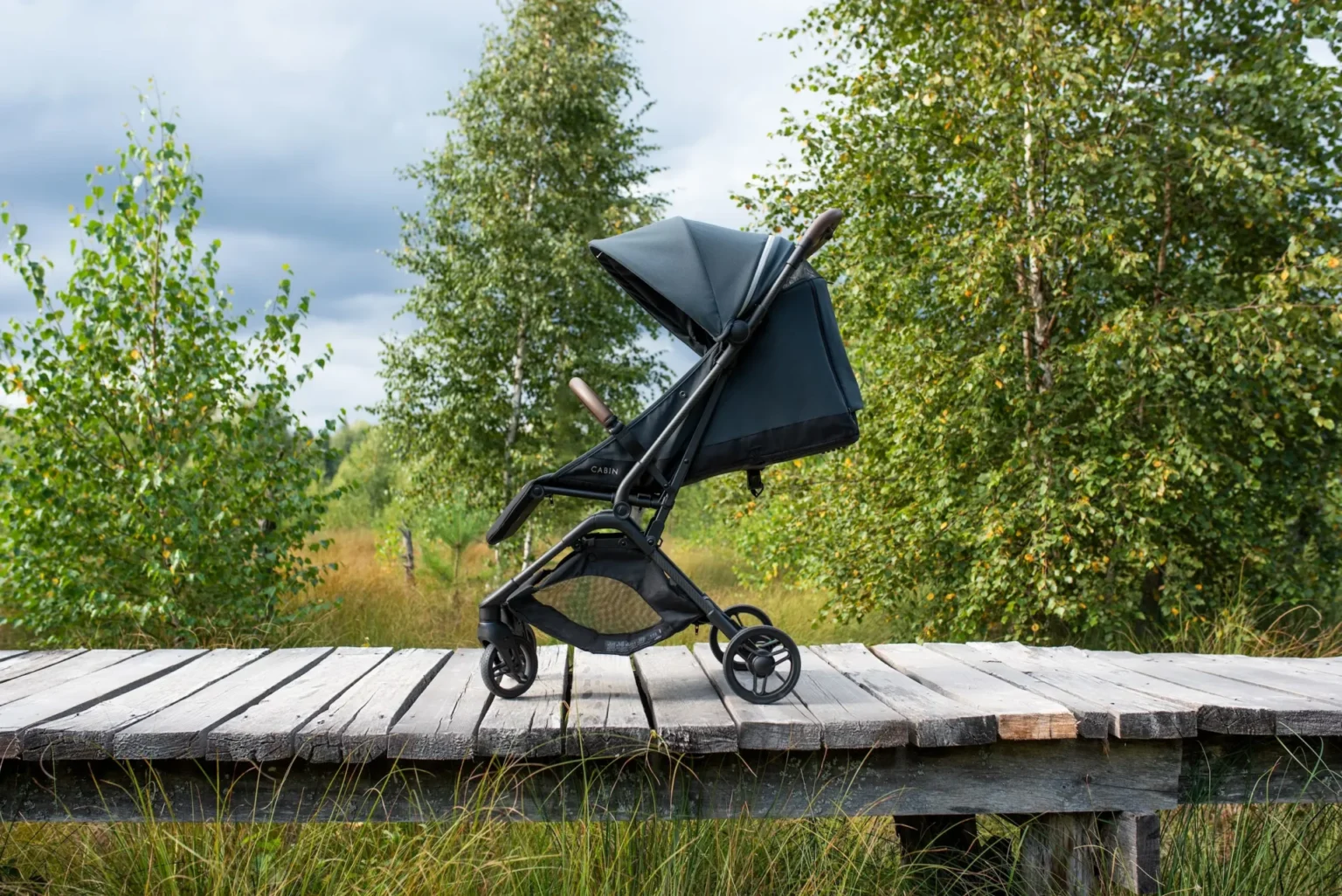 Noordi Sia in Baltic Blue on a wooden boardwalk among birch trees